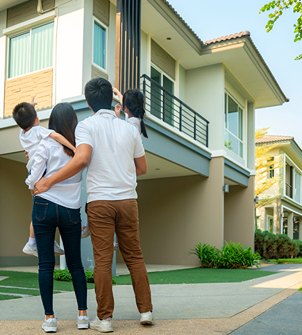 Family standing on sidewalk looking at multifamily property building contemplating resident insurance