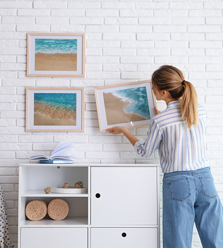 Resident hanging up beach pictures on wall of multifamily property